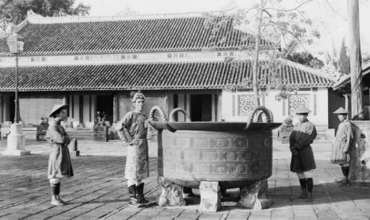 Huế 1920, một võ quan và binh lính đứng cạnh vạc đồng đúc thời chúa Nguyễn đặt trong sân điện Cần Chánh