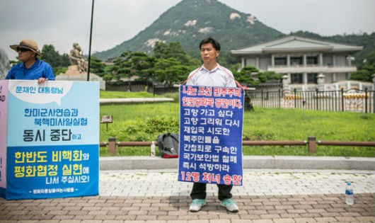 Ông Kwon Chol-nam, người Triều Tiên đào tẩu sang Hàn Quốc năm 2014, giương tấm biển với hàng chữ "Tôi là công dân của Cộng hòa Dân chủ Nhân dân Triều Tiên. Tôi muốn trở về nhà"