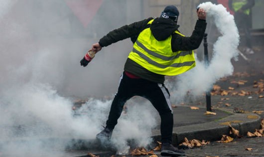 Một người biểu tình ném trả lựu đạn hơi cay về phía cảnh sát ở Paris hôm 1/12
