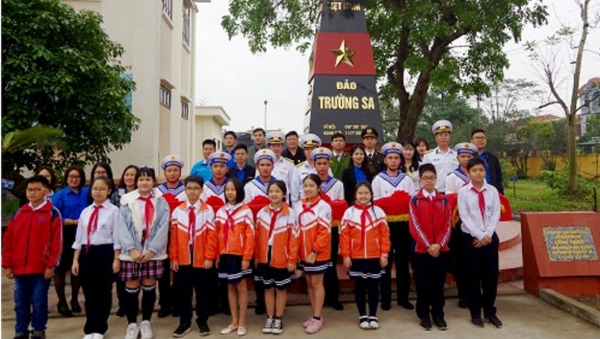 Các đại biểu và các em học sinh chụp ảnh lưu niệm bên cột mốc chủ quyền Trường Sa tại Lữ đoàn 679, Vùng 1 Hải quân