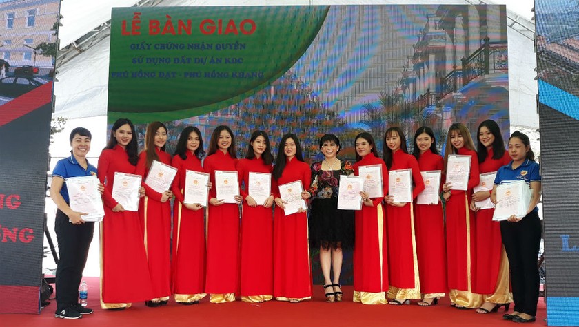 Bà Phạm Thị Hường (đứng giữa) – Chủ tịch Công ty BĐS Phú Hồng Thịnh trao sổ đỏ cho khách hàng.