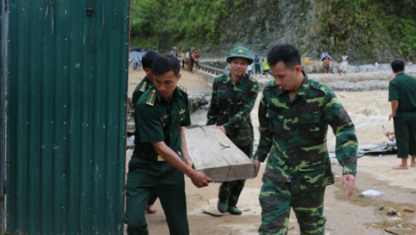 Cán bộ, chiến sĩ Đồn Biên phòng Pa Vệ Sử giúp dân di chuyển đồ đạc ra khỏi vùng sạt lở. Ảnh: Quang Long