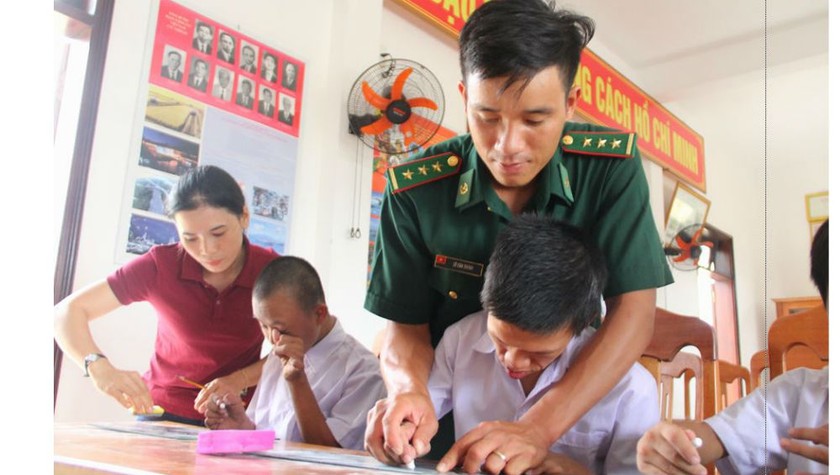 Thầy giáo Chính và cô giáo Ly cầm tay dạy các em từng chữ một. Ảnh: Hồng Anh
