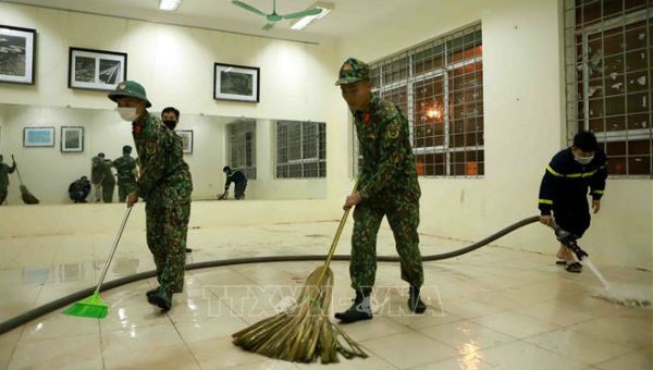 Lực lượng công an, bộ đội dọn vệ sinh các phòng dùng để làm bệnh viện dã chiến (ảnh TTXVN)