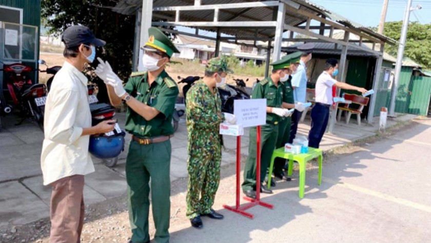 Cán bộ, chiến sĩ Bộ đội Biên phòng An Giang làm nhiệm vụ tại khu vực cửa khẩu phát khẩu trang miễn phí cho du khách qua lại biên giới. Ảnh: Nguyễn Huy.
