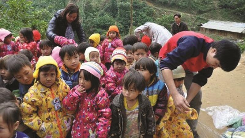 Phóng viên Phạm Diệu cùng Đoàn công tác Báo PLVN tặng áo ấm cho các em nhỏ.
