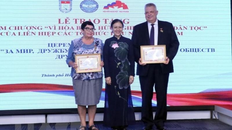 Bà Nguyễn Phương Nga trao tặng Kỷ niệm chương cho ông Aleksei Vladimirovich Popov và bà Natalia Borisovna Zolkina. (Ảnh: Xuân Khu/TTXVN).