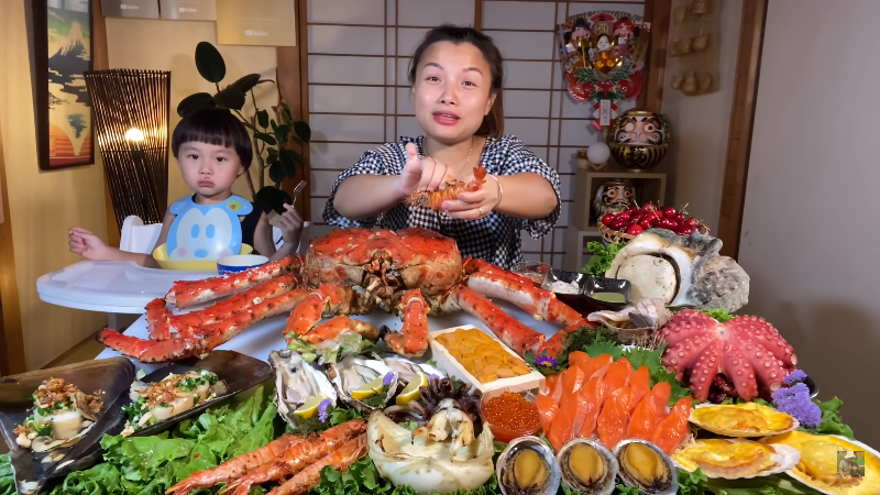 Vlogger Quỳnh Trần JP biểu diễn ăn uống trước mâm thức ăn “ngồn ngộn” trong  clip phát sóng.