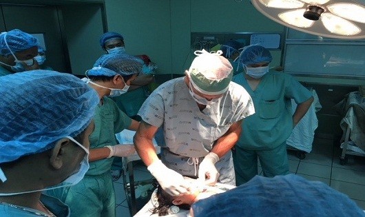 Giáo sư, bác sĩ McKay McKinnon (áo trắng) phẫu thuật khối u quái hàm mặt cho bệnh nhi 16 tháng tuổi