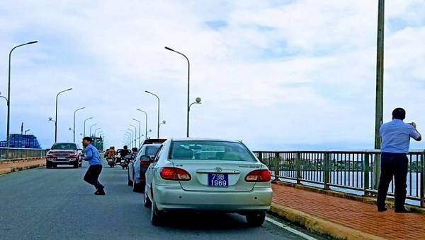 Đoàn xe biển xanh dừng trên cầu Nhật Lệ 1 để chụp ảnh khiến người dân bức xúc. (Ảnh: FB Dương Phong)