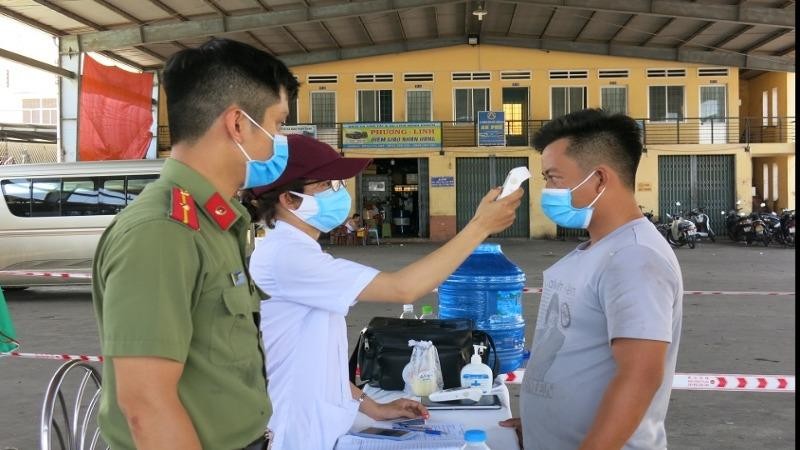 Nhân viên y tế Bình Định kiểm tra thân nhiệt hành khách tại Bến xe khách trung tâm Quy Nhơn. Ảnh: Thu Phương
