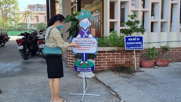 Chị Nguyễn Thị Mai rửa tay sát khuẩn trước khi vào quầy giao dịch.