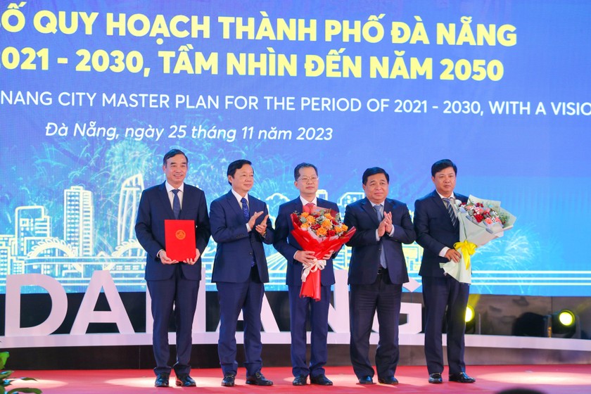 Phó Thủ tướng Trần Hồng Hà và Bộ trưởng Bộ Kế hoạch và Đầu tư Nguyễn Chí Dũng trao quyết định của Thủ tướng Chính phủ về phê duyệt Quy hoạch thành phố Đà Nẵng thời kỳ 2021 - 2030, tầm nhìn đến năm 2050 cho lãnh đạo thành phố. 