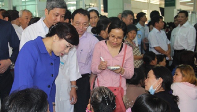 Bộ trưởng Bộ Y tế Nguyễn Thị Kim Tiến (áo xanh) hỏi chuyện bệnh nhân đang chen chúc ngồi chờ khám tại Bệnh viện Chợ Rẫy