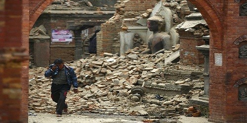 Một người khóc khi đi qua một bức tượng bị phá hủy do động đất ở Nepal. Ảnh: Reuters