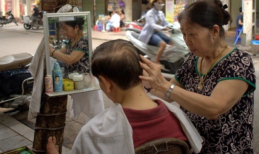 Cụ bà Phạm Thị Xuân Thu đang cắt tóc cho khách.