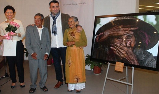 Nhiếp ảnh gia Réhahn và vợ chồng bà Xong đứng cạnh bức ảnh “Nụ cười ẩn giấu”