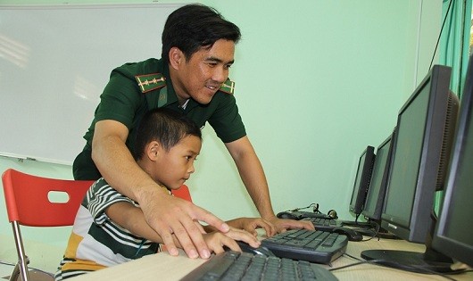 Cán bộ Đồn Biên phòng Cửa khẩu Mỹ Quý Tây đang hướng dẫn cho một em học sinh cách truy cập Internet.
