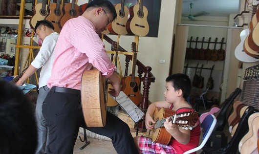 Nghệ sĩ Vũ Đức Hiển đang dạy đàn guitar cho một em nhỏ.