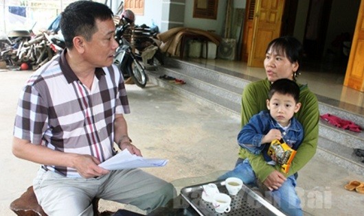 Cán bộ BHXH huyện Yên Bình tuyên truyền chính sách BHYT hộ gia đình đến người dân.