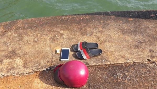Điện thoại, mũ bảo hiểm và đôi dép của chị N. trên bờ.