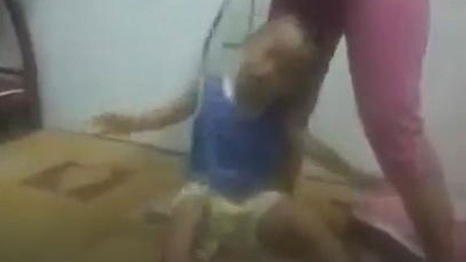 Video ghi lại cảnh một người phụ nữ khoảng 30 tuổi dùng dây thừng buộc vào cổ bé trai khoảng 3 tuổi và dùng vũ lực đánh đập