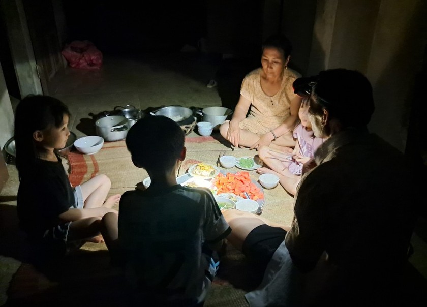 Một gia đình đội đèn pin để dùng cơm tối vì mất điện