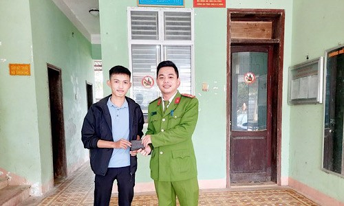 Em Lê Anh Quyết trao trả chiếc ví cho anh Võ Thái Giang - cán bộ Công an huyện Hải Lăng.