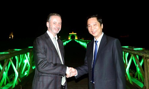 Đại sứ đặc mệnh toàn quyền Cộng hòa Ireland tại Việt Nam John McCullagh và Phó Chủ tịch UBND tỉnh Hoàng Nam đi trên cầu Hiền Lương nhuộm màu xanh. 