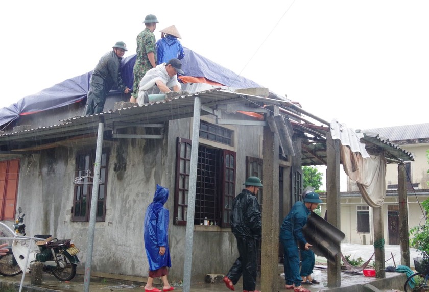 Cán bộ, chiến sĩ Ban CHQS huyện Quảng Điền cùng lực lượng dân quân địa phương khẩn trương giúp dân lợp lại mái nhà bị giông lốc tốc.