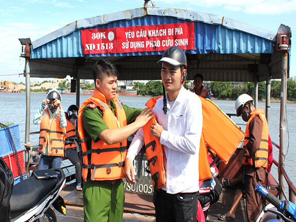 Công an tỉnh Nam Định hướng dẫn hành khách sử dụng áo phao khi tham gia giao thông thủy trên phà Đống Cao.