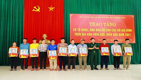 Đại tá Nguyễn Thanh Hải, Chính ủy BĐBP tỉnh Quảng Ninh và Trưởng ban Dân vận Huyện ủy, Chủ tịch MTTQ huyện Bình Liêu trao cờ Tổ quốc và ảnh Bác Hồ cho đại diện các hộ dân.