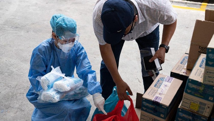 Tình nguyện viên phát vật tư y tế cho người lao động nước ngoài tại ký túc xá. Ảnh CNN. 