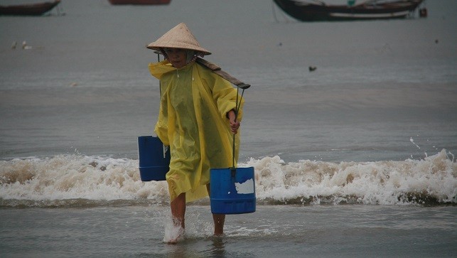 Bà Huỳnh Thị Côi mặc chiếc áo tơi miệt mài gánh nước.