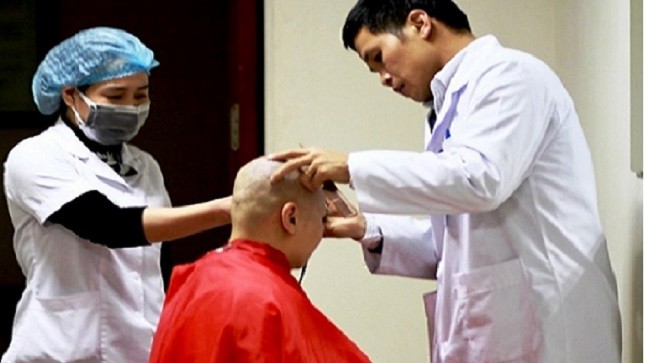 Bác sĩ Hưng đang hướng dẫn y tá cắt tóc cho bệnh nhân.