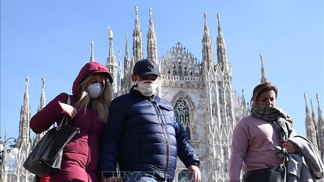 Khách du lịch đeo khẩu trang phòng dịch COVID-19 khi thăm quan Nhà thờ lớn Duomo tại Milan, Italy. Ảnh tư liệu: THX/TTXVN