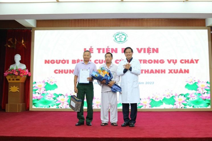 PGS.TS Đào Xuân Cơ, Giám đốc Bệnh viện Bạch Mai đã trao tặng bệnh nhân hoa và quà chúc mừng bệnh nhân ra viện. Ảnh: Thành Dương