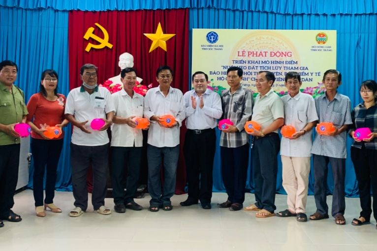 Ông Lâm Thanh Thiên - Phó Giám đốc BHXH tỉnh (thứ 6 từ phải sang) trao tặng heo đất cho hội viên nông dân tham gia mô hình