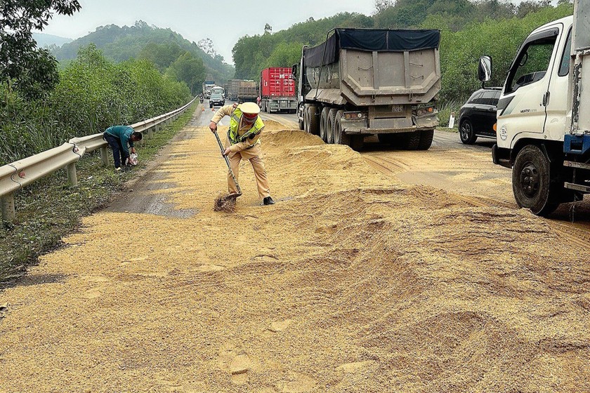 Hình ảnh chiến sỹ CSGT Công an Nghệ An đang cào cát để xử lý dầu tràn ra đường.