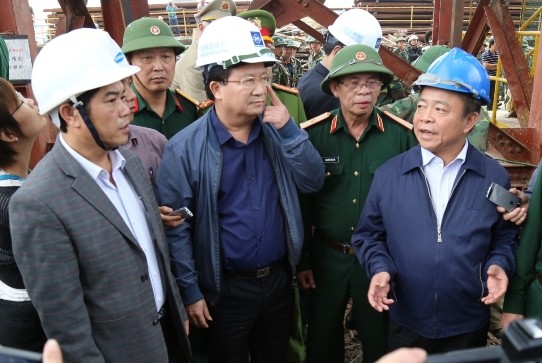 Bộ trưởng Trịnh Đình Dũng (giữa) và Bí thư Tỉnh ủy Võ Kim Cự (phải, mũ xanh) chỉ đọa tại hiện trường.