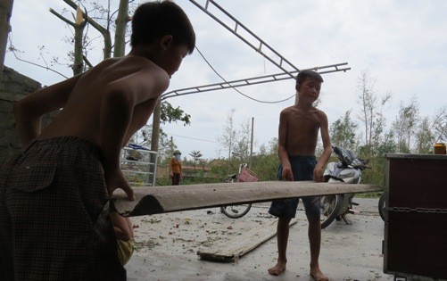 Hai em nhỏ ở thôn Thọ Sơn, xã Quảng Đông giúp đỡ gia dọn dẹp mái nhà bị bão đánh tan. 