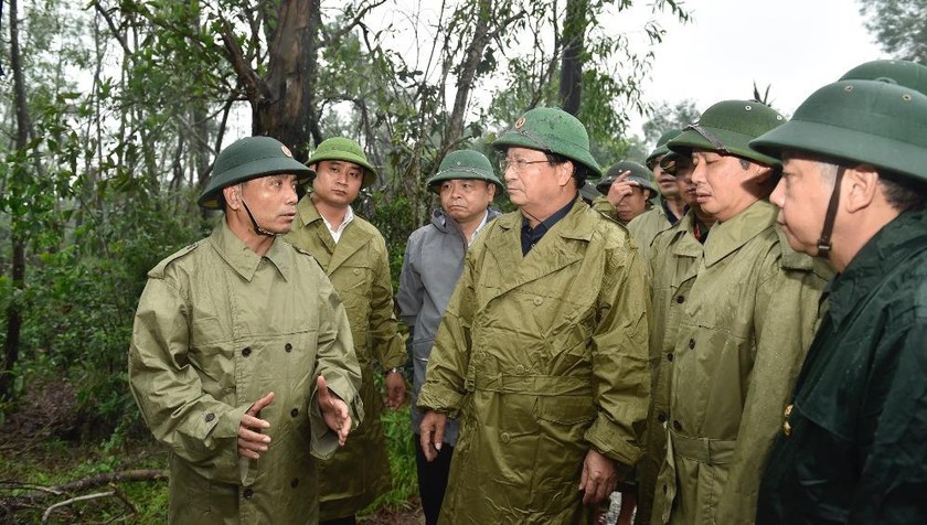 Tư lệnh Quân khu 4 Nguyễn Doãn Anh (bìa trái) báo cáo tình hình với Phó thủ tướng Trịnh Đình Dũng (giữa) tại huyện Phong Điền, Thừa Thiên Huế, chiều 13/10. Ảnh: VGP/Nhật Bắc