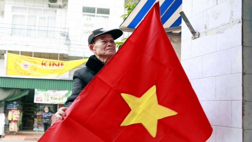 Đảng viên lão thành ở khu Quang Trung (thị trấn Tiên Yên, Quảng Ninh) nâng niu lá cờ Tổ quốc để treo trước cửa nhà chào mừng Đại hội đại biểu toàn quốc lần thứ XIII của Đảng. Ảnh: baoquangninh