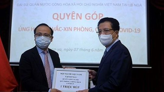 Đại sứ Đặng Minh Khôi tiếp nhận tượng trưng số tiền 1 triệu Ruble (tương đương 13.500 USD) do Hội người Việt Nam tại Nga quyên góp ủng hộ Quỹ vaccine phòng COVID-19. Ảnh: TTXVN