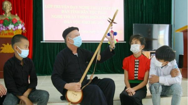 Nghệ nhân Lò Văn Sơi dân tộc Thái hướng dẫn học viên nhỏ tuổi về kỹ năng học đàn tính. Ảnh: Tùng Phương.