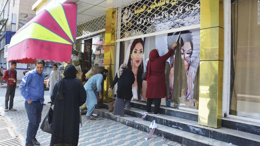 Các công nhân tại một thẩm mỹ viện ở Kabul bóc những tấm ảnh lớn có hình phụ nữ vào ngày 15/8/2021. Ảnh: CNN.