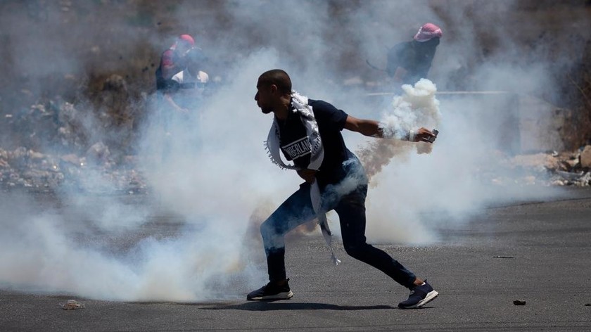 Một người biểu tình Palestine ném lại một ống đựng hơi cay do lực lượng Israel bắn trong cuộc biểu tình ở thành phố Ramallah, Bờ Tây ngày 17/8/2021. Ảnh: AP
