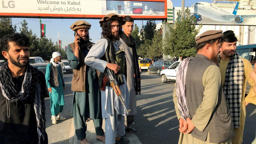 Một thành viên của Taliban cùng người dân đứng bên ngoài sân bay quốc tế Hamid Karzai ở Kabul, Afghanistan hôm 16/8. Ảnh: Reuters
