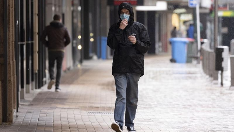 Một người đàn ông đeo khẩu trang đi bộ trên phố ở Wellington vào ngày 18/8/2021 khi New Zealand thực hiện lệnh phong tỏa toàn quốc để chống dịch COVID-19. Ảnh: AFP