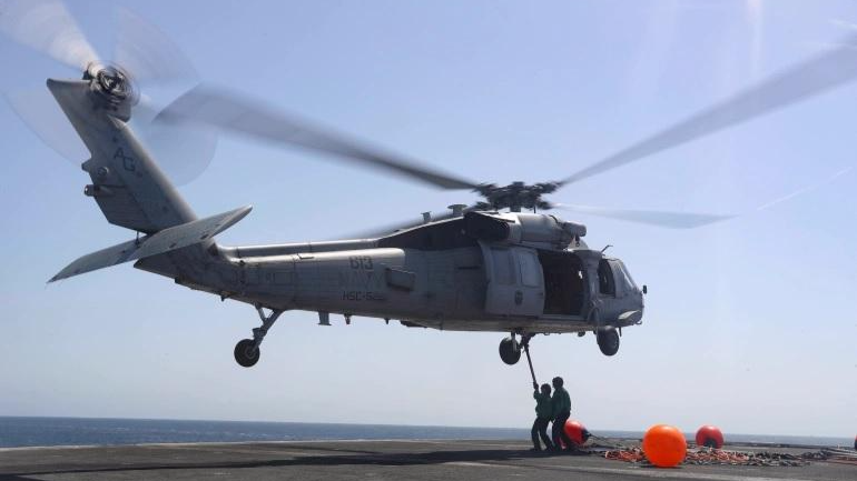 Các thủy thủ Hải quân Hoa Kỳ đang kết nối các thanh pogo, được sử dụng để vận chuyển hàng hóa, với trực thăng MH-60S vào tháng 6/2019. Ảnh: Reuters